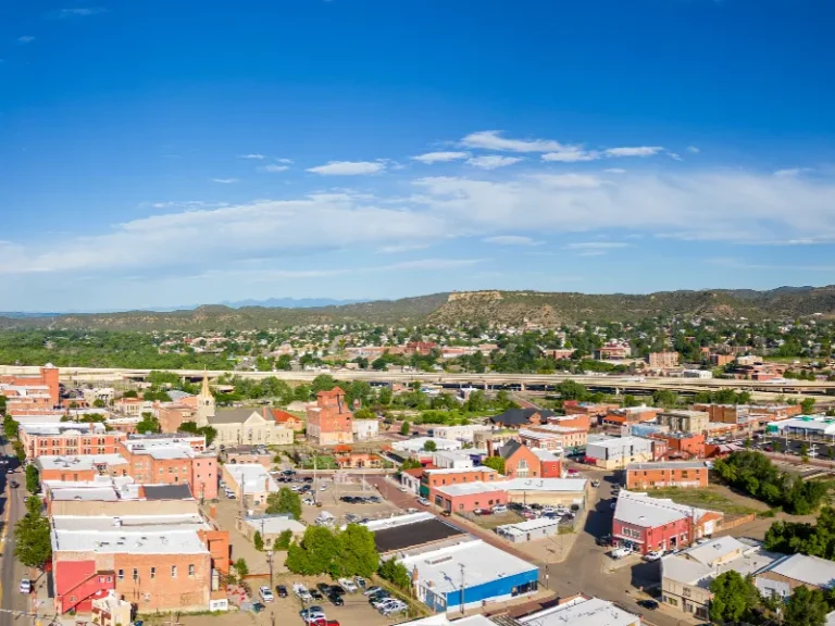 Small town with brick buildings and a highway in the background under a blue sky.