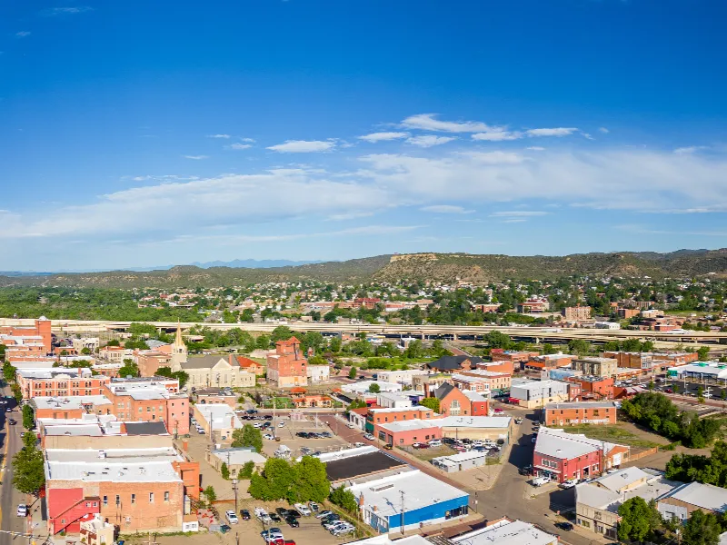 Small town with brick buildings and a highway in the background under a blue sky.
